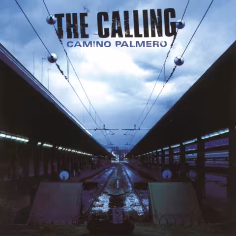Front cover of Camino Palmero: a symmetrical view down two covered railway platforms towards a distant vanishing point, wet tracks gleaming between them and overhead wires strung with round globes beneath a stormy blue sky, with THE CALLING in distressed black capitals across the top and CAMINO PALMERO in smaller blue letters below.