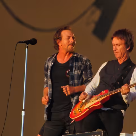 Eddie Vedder of Pearl Jam singing into a microphone beside guitarist Johnny Marr at BST Hyde Park in London in July 2022.