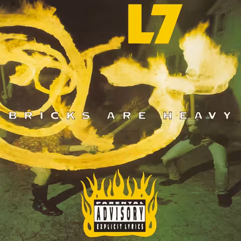 Cover of L7's Bricks Are Heavy: a green-tinted long-exposure night photo of two fire performers spinning looping trails of flame, with the band name in yellow and a flaming parental advisory sticker.