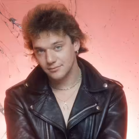 Paul Di'Anno performing live in the early 1980s during his Iron Maiden years, microphone in hand and snarling at the front of the stage.