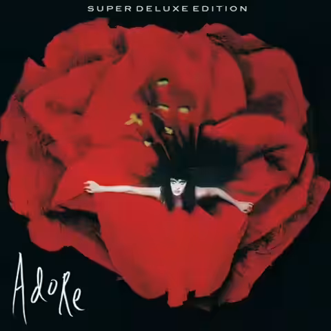 Front cover of Adore by The Smashing Pumpkins, a black-and-white Yelena Yemchuk photograph of model Amy Wesson leaning forward, holding the ends of a flowing black dress, with the album title scrawled in white handwriting.