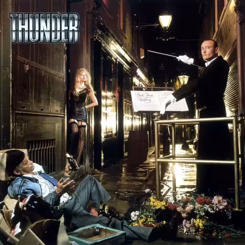 Front cover of Thunder's debut album Backstreet Symphony, photographed by Andy Earl in London's Artillery Passage, showing drummer Gary James, a man dressed as a tramp and a woman in a Victorian-brick alleyway lit by a single sodium lamp.