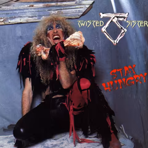 Front cover of Stay Hungry by Twisted Sister, photographed by Mark Weiss in 1984: Dee Snider in heavy stage makeup and a torn pink-and-black costume, baring teeth around a raw beef bone against a black background.