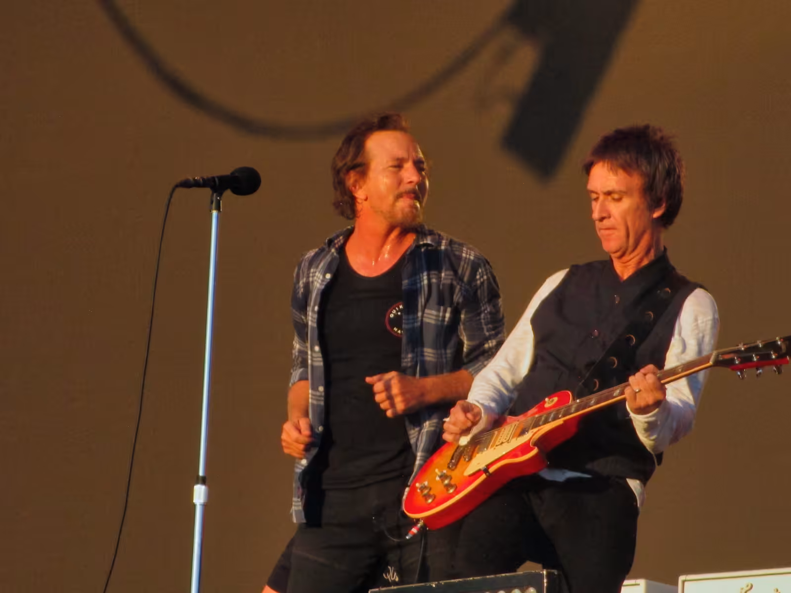Eddie Vedder of Pearl Jam singing into a microphone beside guitarist Johnny Marr at BST Hyde Park in London in July 2022.