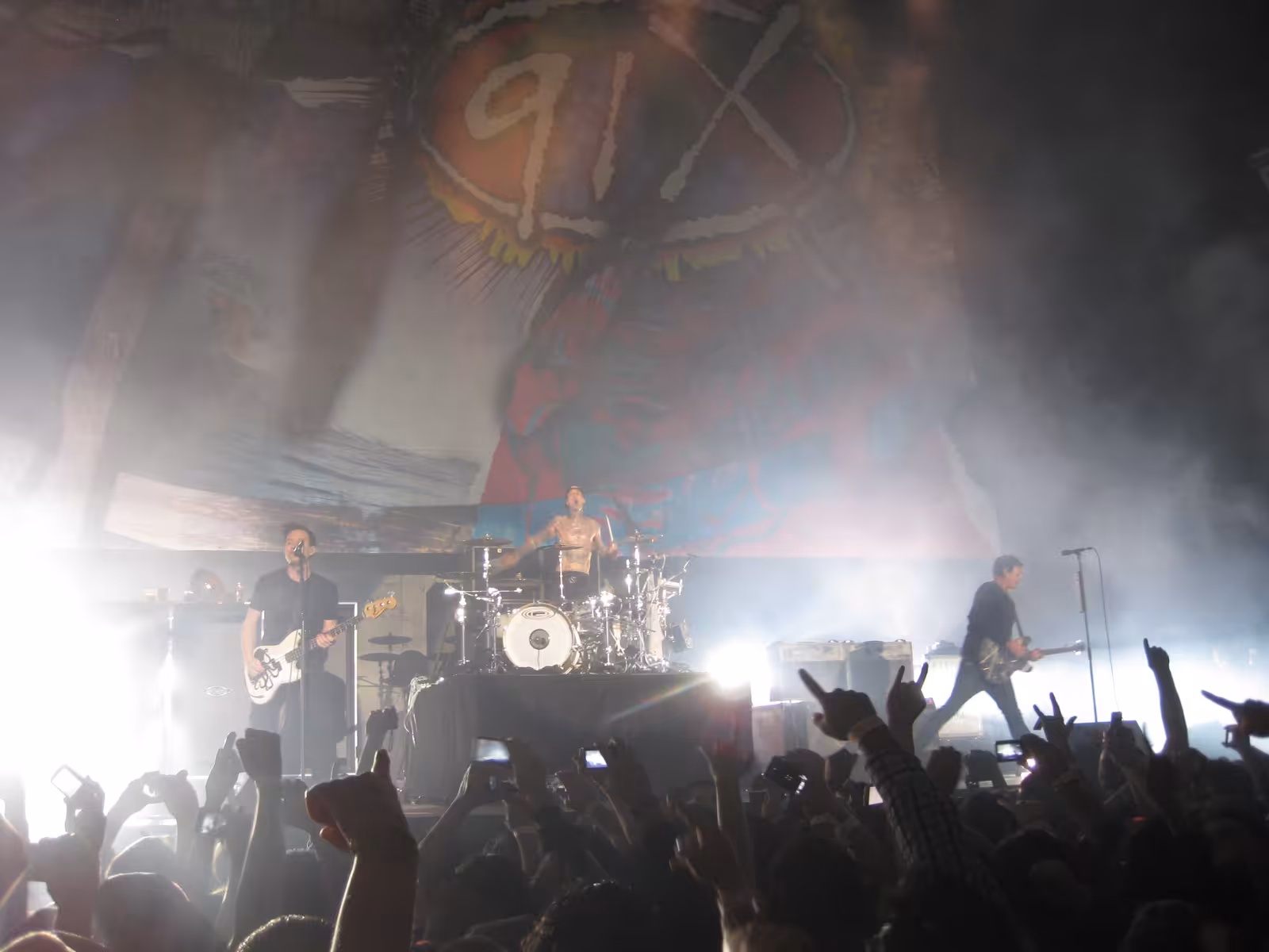 Blink-182 performing live in San Diego in 2011 with Mark Hoppus and Tom DeLonge on guitars and Travis Barker on drums behind them.