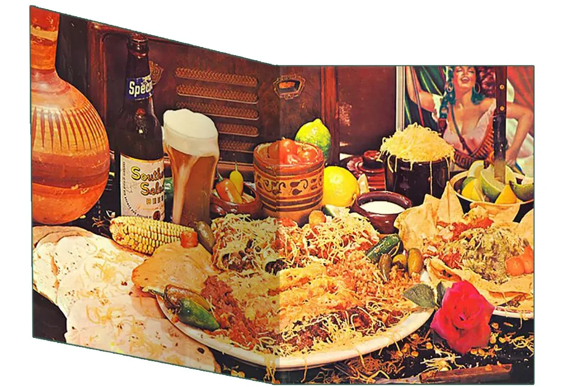 The inside gatefold photograph from Tres Hombres: a Tex-Mex feast of enchiladas, tacos, nachos, beans, limes and peppers spread across a wooden table with a frothy beer mug and an antique radio.