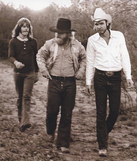 Sepia-toned 1973 promotional photo of ZZ Top walking down a Texas dirt track: long-haired Frank Beard on the left, Dusty Hill in a black hat and early beard in the centre, and Billy Gibbons in a white shirt and pale cowboy hat on the right.